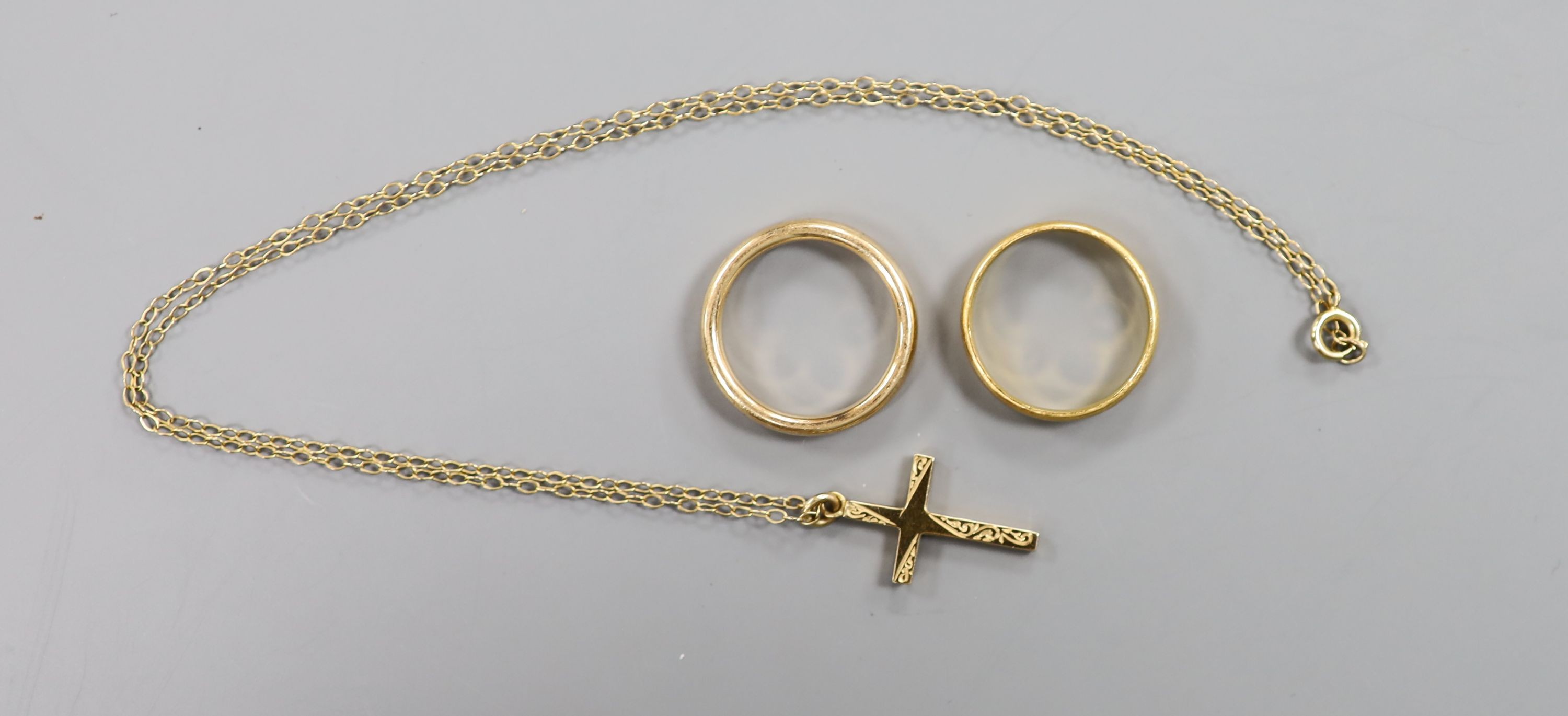 A 22ct god wedding band, 3.7 grams, a yellow meta wedding band, 5 grams and a modern 9ct gold cross pendant on a fine link chain, gross 2.1 grams.